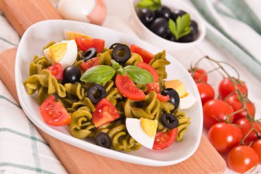 Fusilli pasta with cherry tomatoes, eggs and black olives.