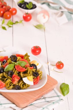 Fusilli pasta with cherry tomatoes, eggs and black olives.