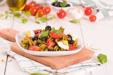 Fusilli pasta with cherry tomatoes, eggs and black olives.