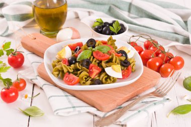 Fusilli pasta with cherry tomatoes, eggs and black olives.