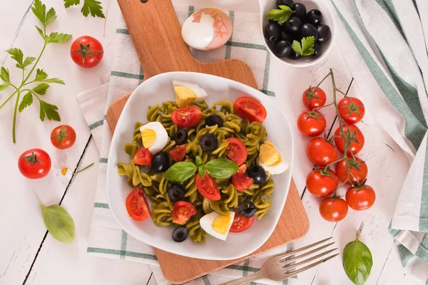 Fusilli pasta with cherry tomatoes, eggs and black olives.
