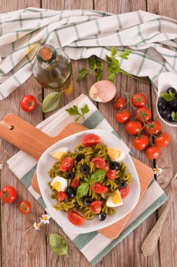 Fusilli pasta with cherry tomatoes, eggs and black olives.