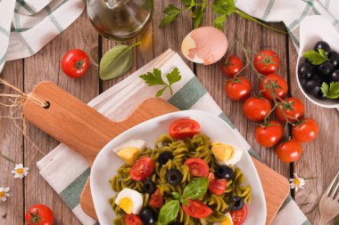 Fusilli pasta with cherry tomatoes, eggs and black olives.