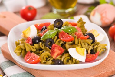 Fusilli pasta with cherry tomatoes, eggs and black olives.