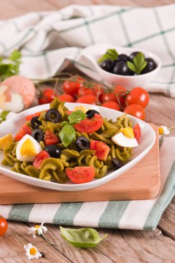 Fusilli pasta with cherry tomatoes, eggs and black olives.
