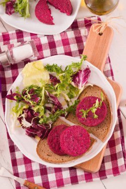 Beyaz tabakta salatalı pancar vejetaryen burger.
