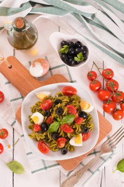 Fusilli pasta with cherry tomatoes, eggs and black olives.