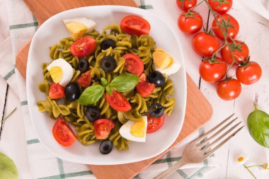 Fusilli pasta with cherry tomatoes, eggs and black olives.