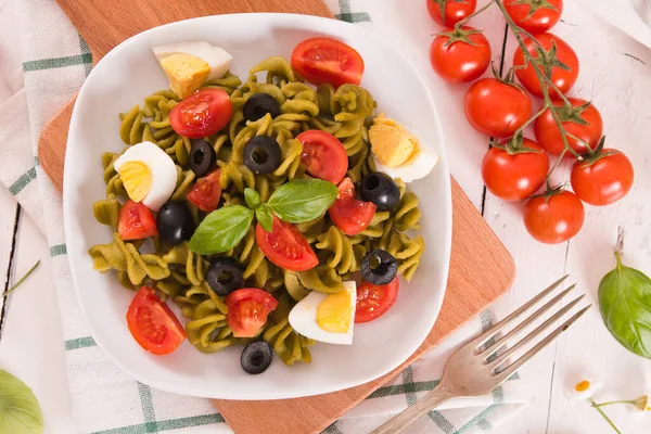 Fusilli pasta with cherry tomatoes, eggs and black olives.