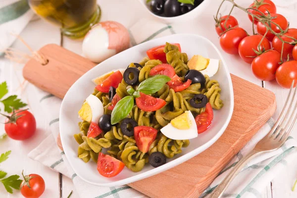 Fusilli pasta with cherry tomatoes, eggs and black olives.