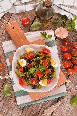 Fusilli pasta with cherry tomatoes, eggs and black olives.