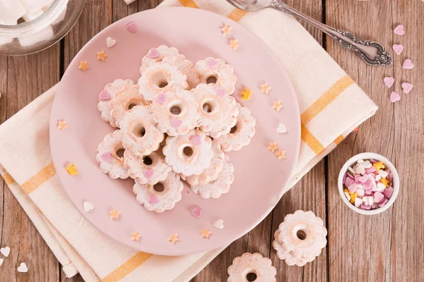 Canestrelli biscuits with icing sugar on pink dish.
