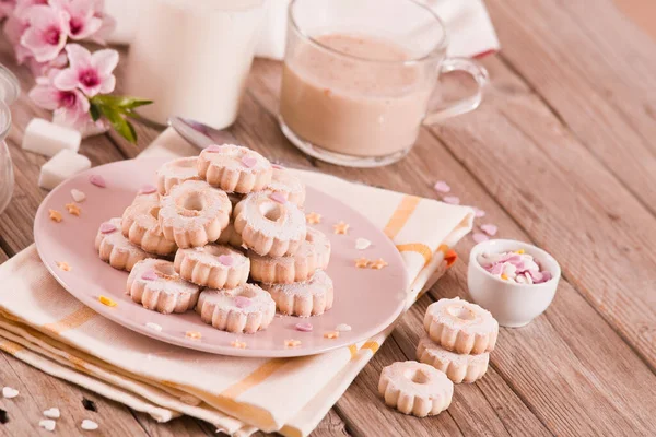 Canestrelli biscuits with icing sugar on pink dish.