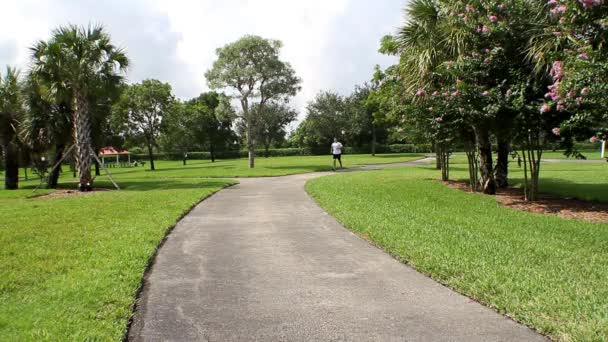 Спортивный человек в белом бегает в парке — стоковое видео
