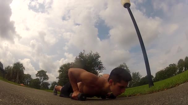 Hombre en ropa deportiva haciendo flexiones. Entrenamiento al aire libre — Vídeos de Stock