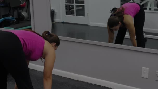 Mujer joven con cuerpo deportivo estirándose y relajándose en el gimnasio — Vídeos de Stock