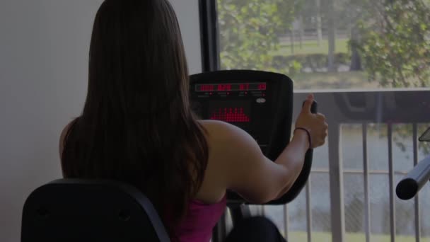 Frau trainiert auf stationärem Fahrrad in Fitnessstudio — Stockvideo