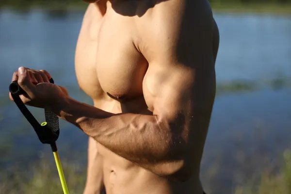 Muscular super-high level man pulls rubber bands — Stock Photo, Image