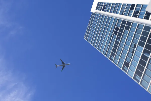Avião voando acima de um arranha-céu — Fotografia de Stock