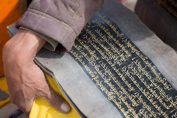 Old Tibetan language on old paper and the hand of a monk — Stock Photo, Image