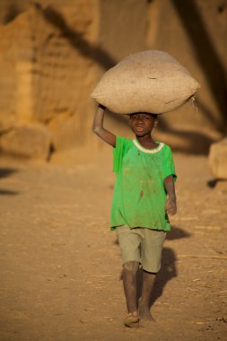bir torba pirinç mali dogon ülke içinde taşıyan çocuk