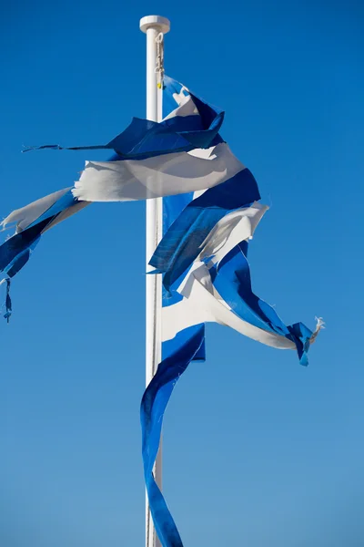 Una bandera griega rota con un cielo azul claro — Foto de Stock