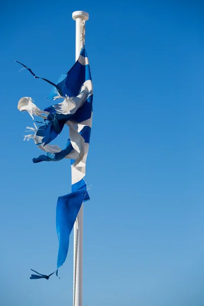 Una bandiera greca rotta con un cielo blu chiaro — Foto Stock