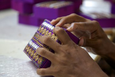 Close-up of hands working on a purple box in India clipart