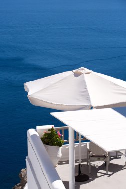 beyaz şemsiye ve calder terasta dinlendirici bir sandalyede