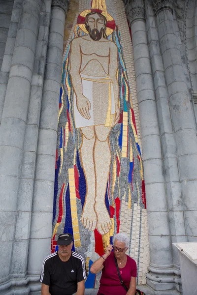 Casal sentado na frente de uma enorme escultura de Jesus em mosaico em L — Fotografia de Stock