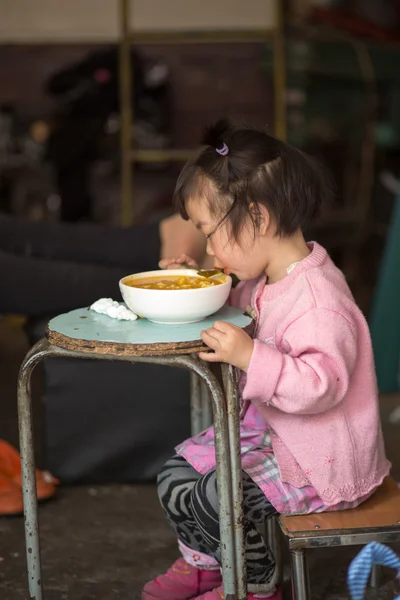 Junges Mädchen isst auf einem blauen Tisch in Shanghai — Stockfoto