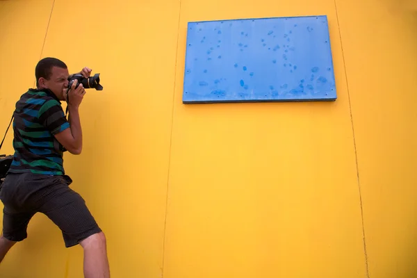 Uomo scattare una foto di fronte a un muro giallo appariscente — Foto Stock