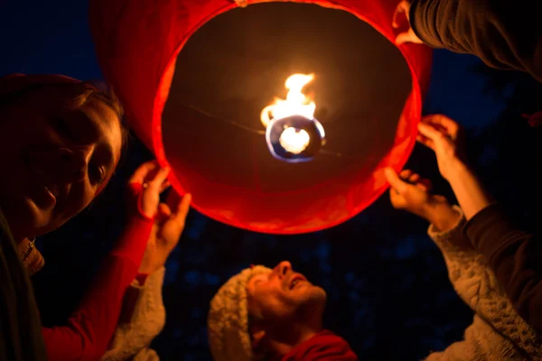 People manipulating a flying lantern during a party in a garden — Stock Photo, Image