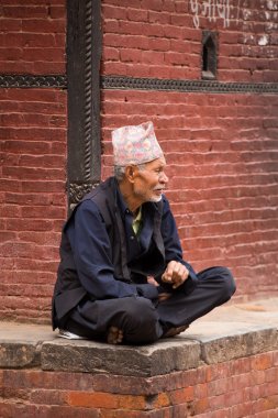 Old man resting and obsertving the street activity in Nepal clipart