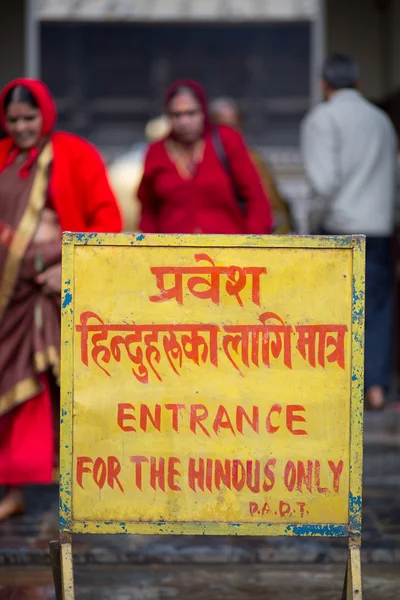 Gele bord tegenover een hindoe tempel in kathmandu. — Stockfoto