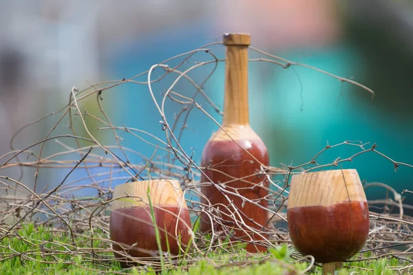 Wooden bottle and glasses with grass and branches around — Stock Photo, Image