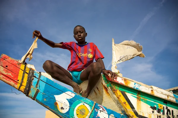 Kid zittend op een gekleurde fisher boot in senegal — Stockfoto