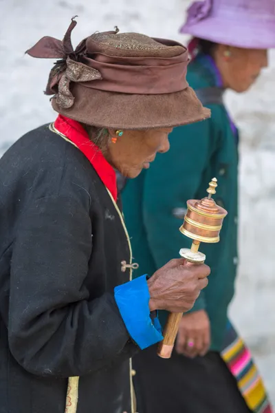 Старуха молится с молитвенным рулоном в Лхасе — стоковое фото