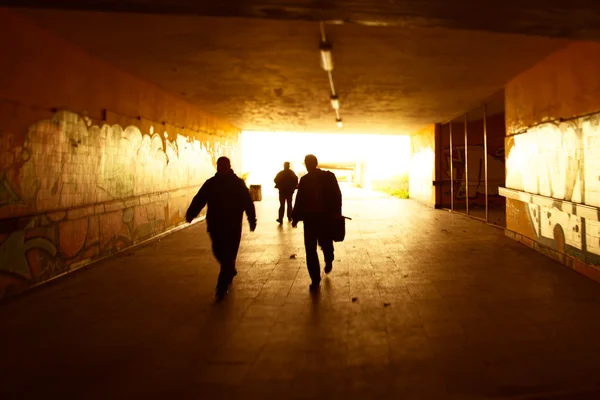 Силуэты, идущие в городской гранж-тоннель — стоковое фото