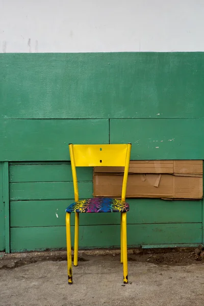 Vieille chaise métallique jaune avec fond en bois — Photo