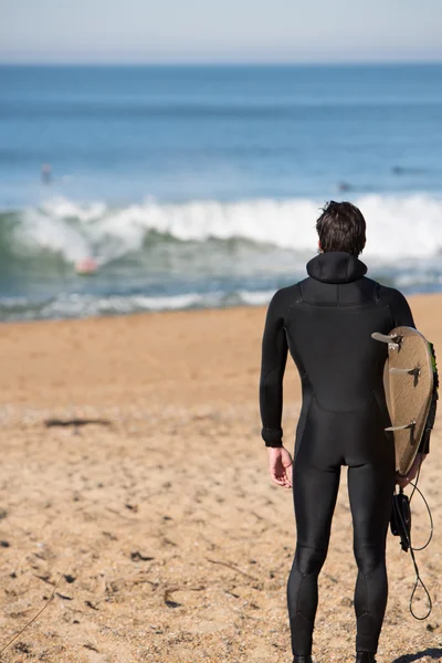Jeune surfeur debout sur une plage et portant son surf bo — Photo