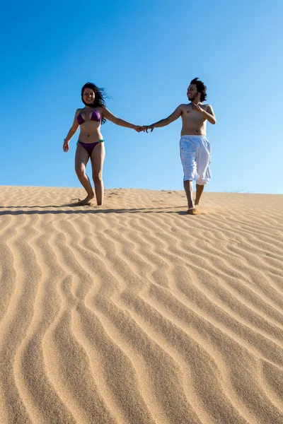 Bonito e feliz jovem casal andando na areia — Fotografia de Stock