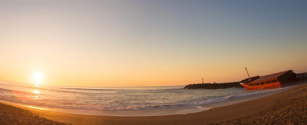 Zeegezicht zonsondergang met schipbreuk op het strand — Stockfoto