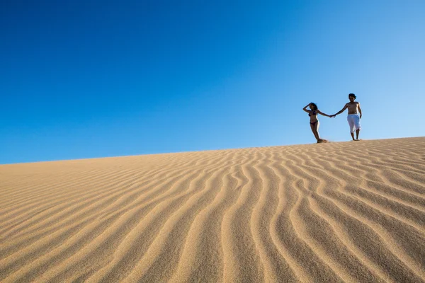 Bonito e feliz jovem casal andando na areia — Fotografia de Stock