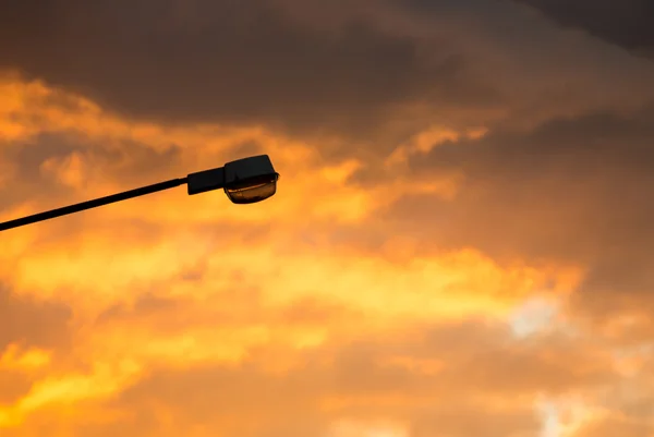 Luz de rua contra o crepúsculo de fundo do pôr do sol e nuvens — Fotografia de Stock