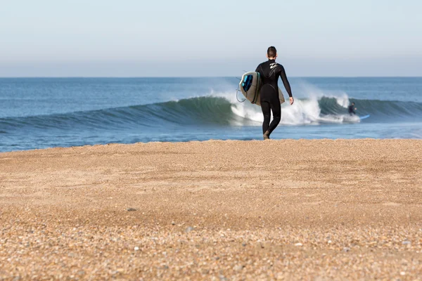 Jovem com prancha de surf andando na praia — Fotografia de Stock
