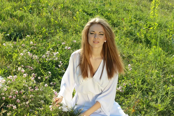 Vrouw zitten op het gras buitenshuis — Stockfoto