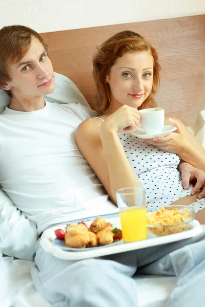 若いカップルはベッドで朝食をとる — ストック写真