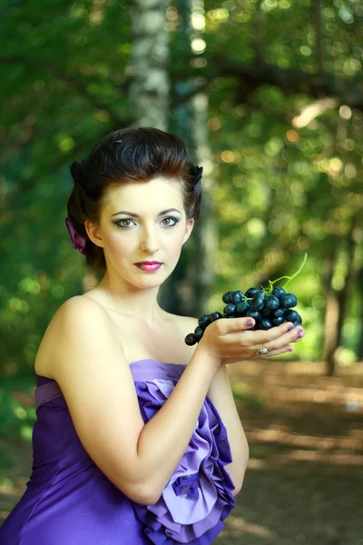 Vrouw donker blauwe druiven — Stockfoto