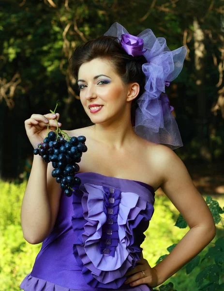 Woman in violet fashion dress grapes — Stock Photo, Image